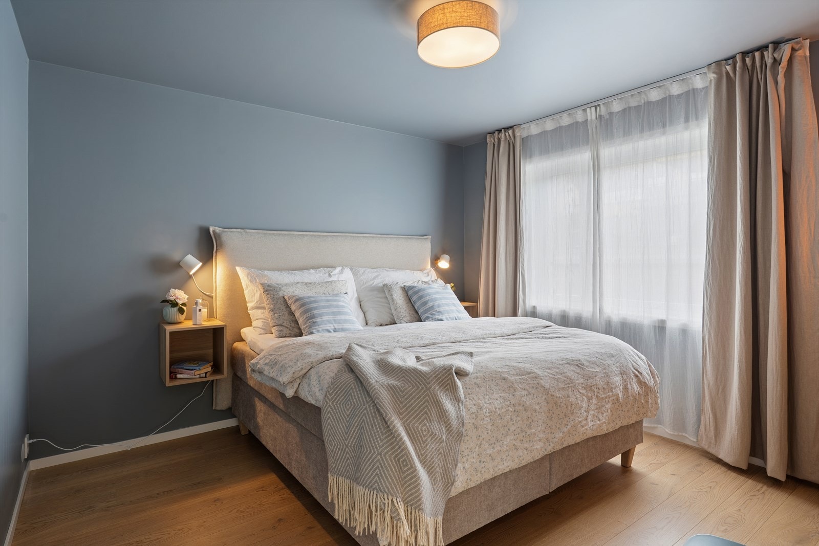 Hovedsoverommet er utformet som et rolig og harmonisk tilfluktssted, malt i en dus blåfarge på både vegger og tak. Fargevalget gir rommet en lun og omsluttende atmosfære som inviterer til avslapning og restitusjon etter lange dager. Galleribilde