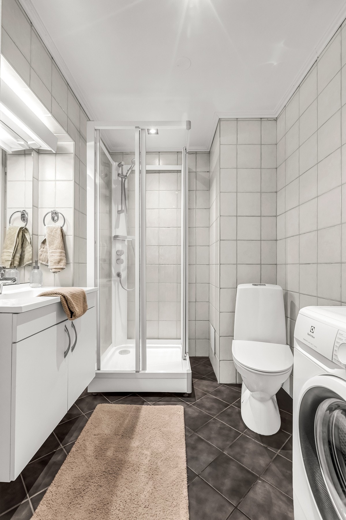 Flislagt baderom med gulvvarme. Badet er utstyrt med servantskap, servant, speil, toalett og dusjkabinett. Galleribilde