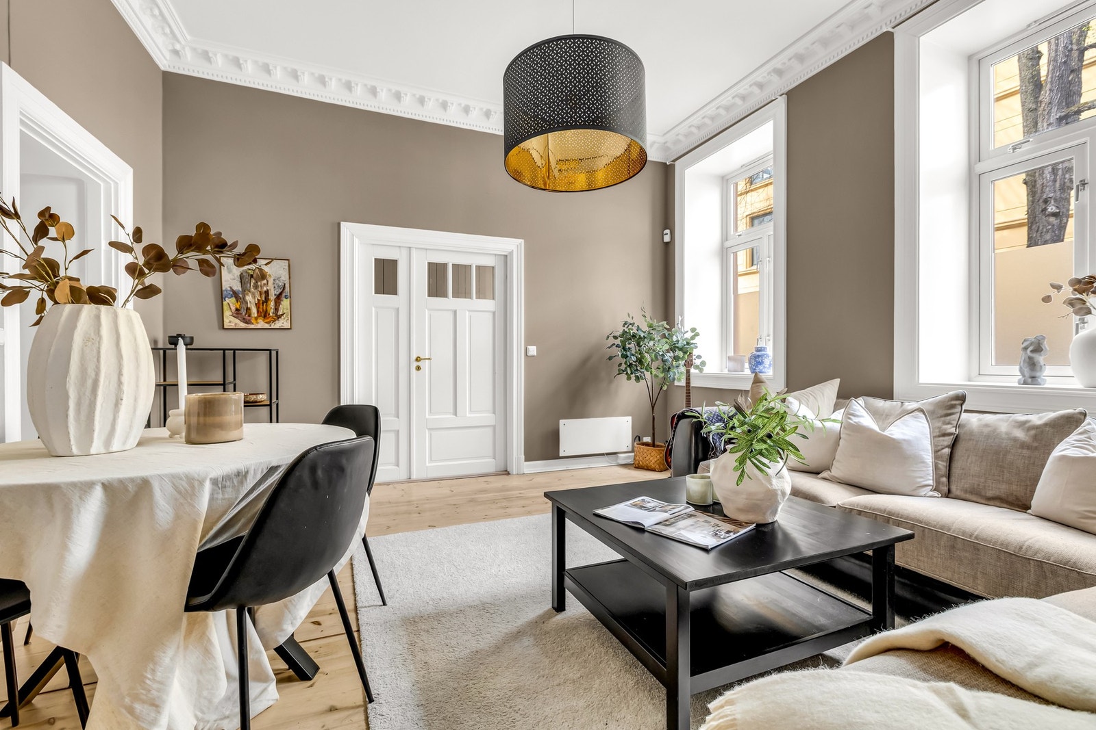 Stuen fremstår som romslig og innbydende, med klassiske detaljer som stukkatur og rosett. Galleribilde