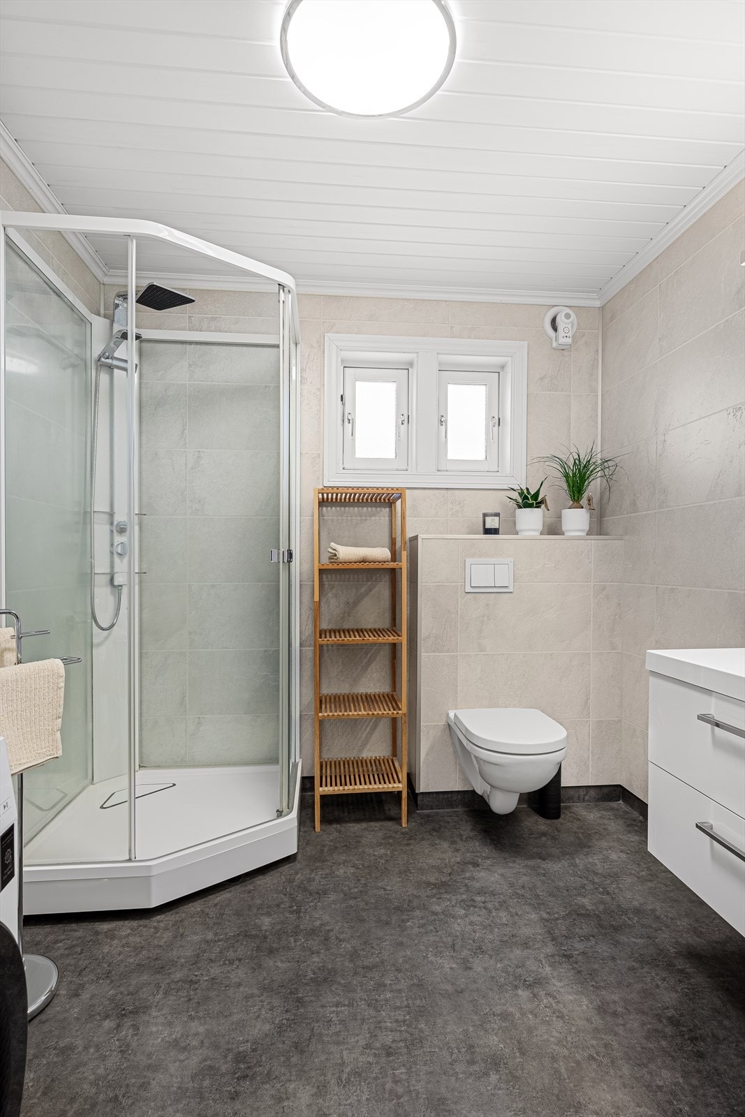Badet er innredet med vegghengt toalett, servant med skuffer, speilskap, dusjkabinett og opplegg for vaskemaskin. Galleribilde