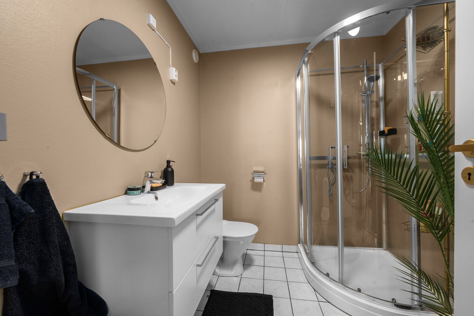 Badet i hybelen har flislagt gulv med varmekabler, dusjkabinett og opplegg for vaskemaskin. Galleribilde