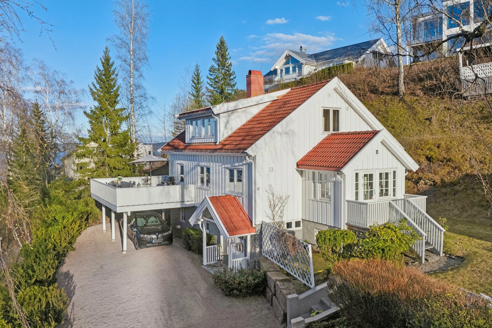 Boligen har carport med el.bil-lader og i oppkjørselen er det plass til å parkere flere biler. Galleribilde