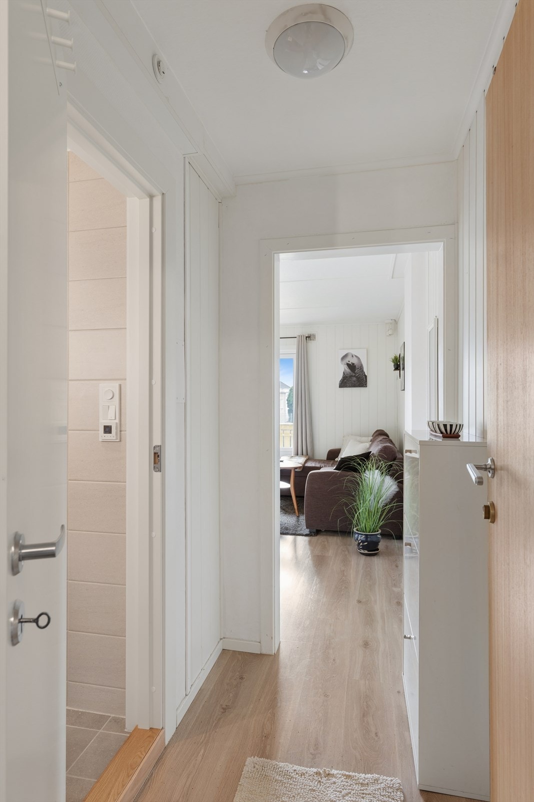 Man kommer inn i entrè med praktisk laminat på gulv og malt panel på vegg Galleribilde
