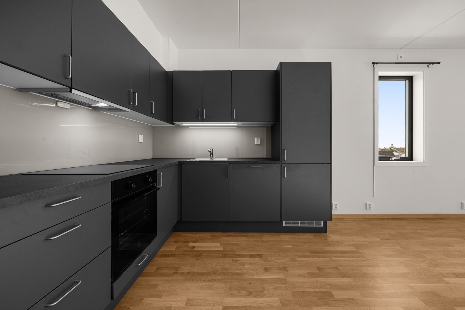 Kjøkkeninnredning med mørke, glatte fronter og laminatbenkeplate. Alle hvitevarer er integrert. Galleribilde