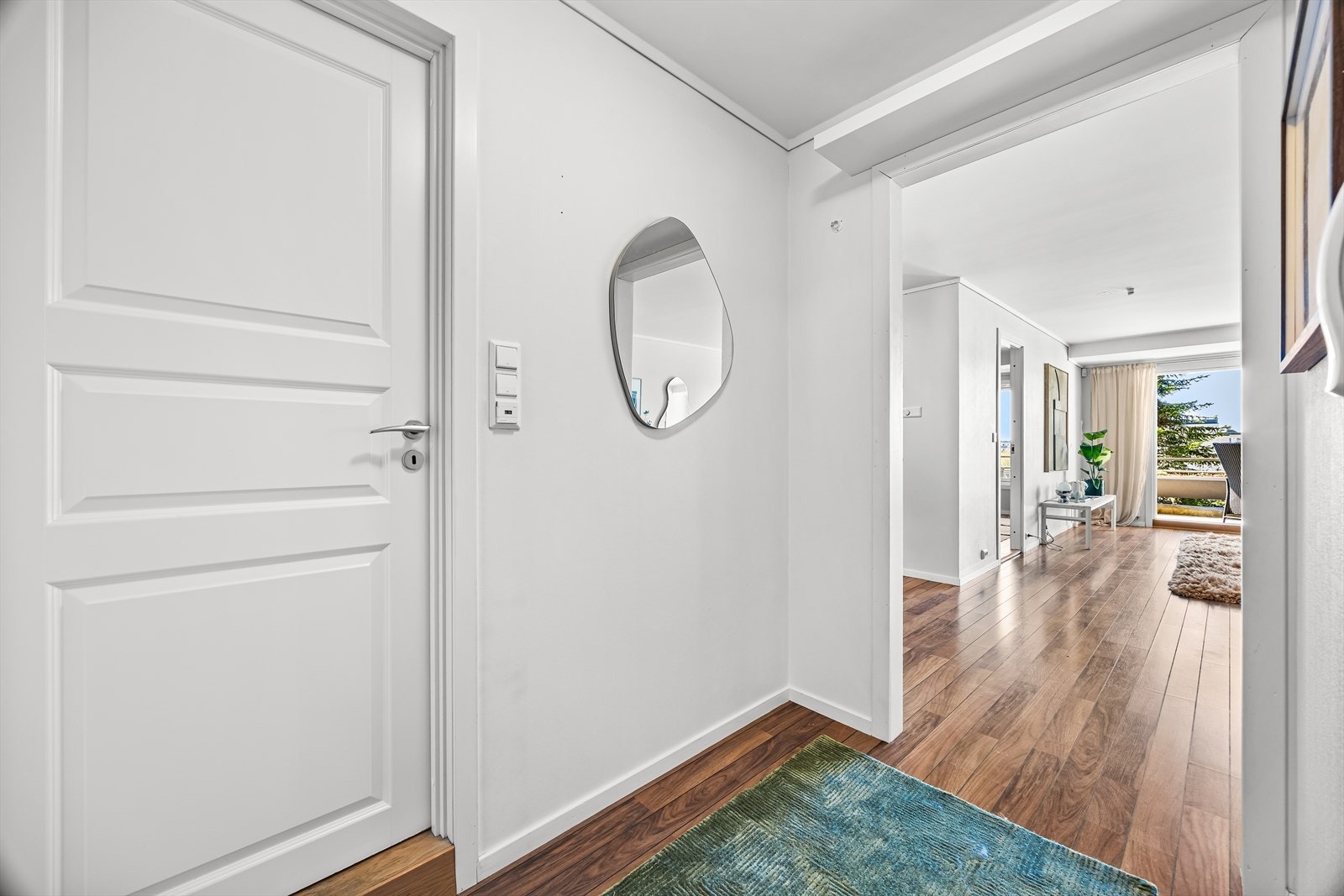 Døren åpner inn til en entré som leder videre inn i leilighetens åpne sone. Galleribilde