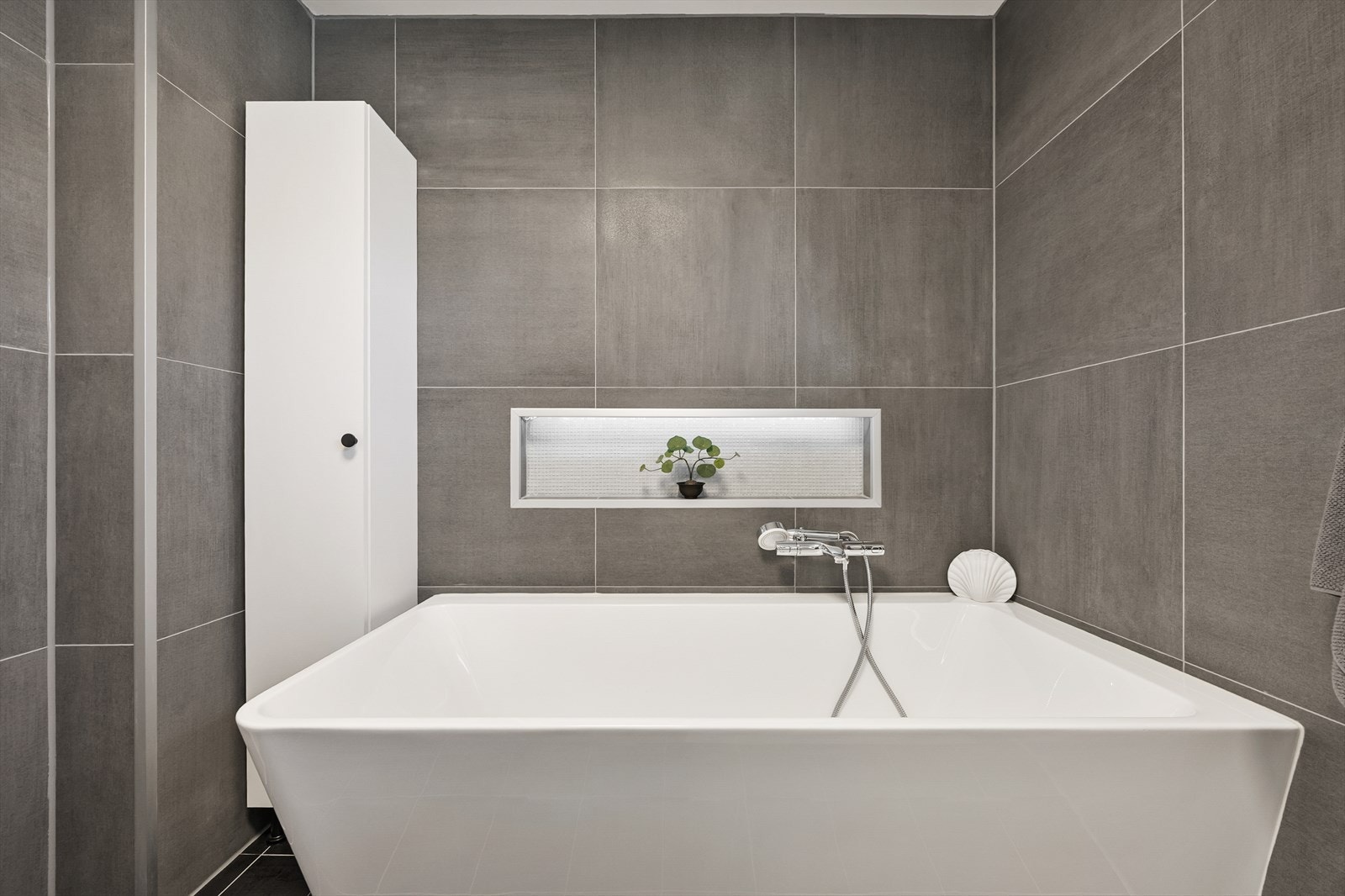 Badet har vegghengt toalett og et badekar med dusjløsning. Galleribilde