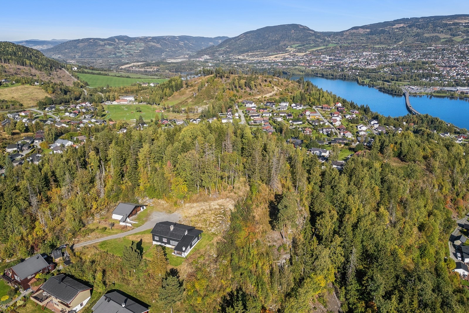 Eiendommen ligger høyt og fritt til, omgitt av skog og etablert eneboligbebyggelse. Galleribilde