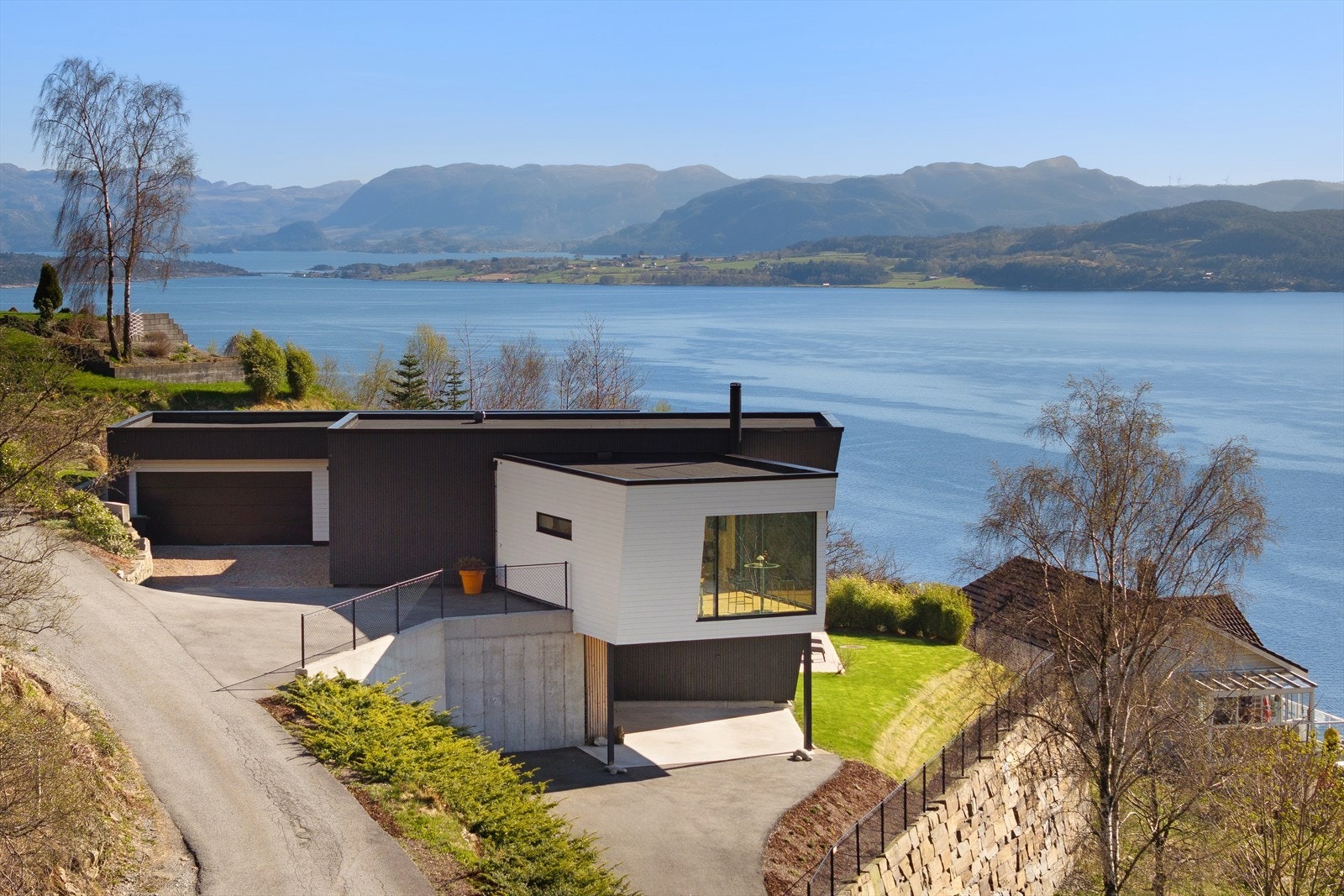 Eiendommen ligger høyt og fritt i et skrånende terreng, med dobbel garasje og asfaltert adkomst, samt en formidabel utsikt over fjord og fjell. Galleribilde