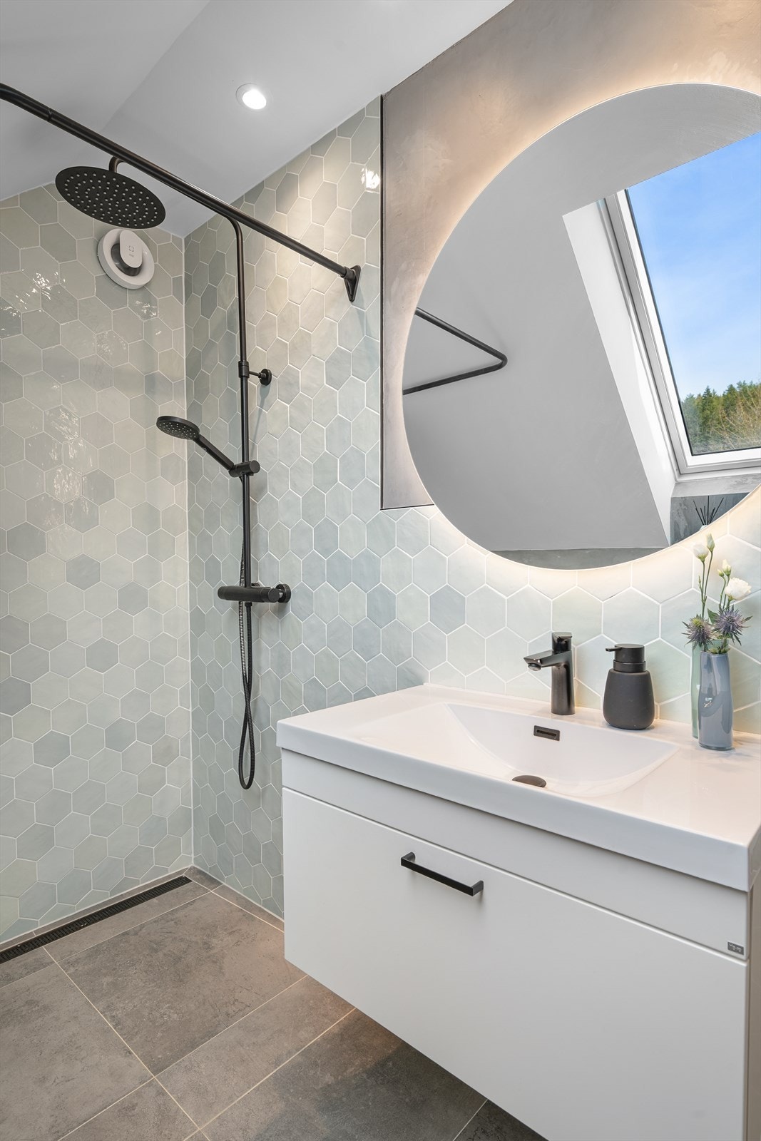 Det runde speilet med integrert belysning gir en myk kontrast til de stramme linjene. Badet ble pusset opp i årsskifte 2023/2024. Galleribilde