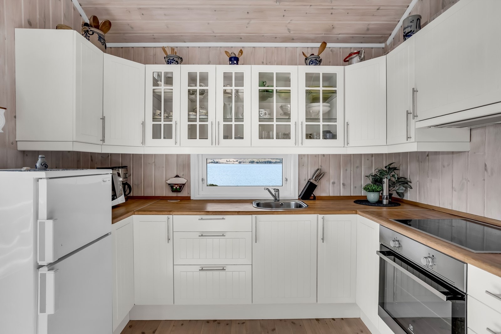 Kjøkkeninnredning med profilerte fronter, benkeplate i heltre og overskap med glassfelt. Det er plass for integrert stekeovn og koketopp. Galleribilde