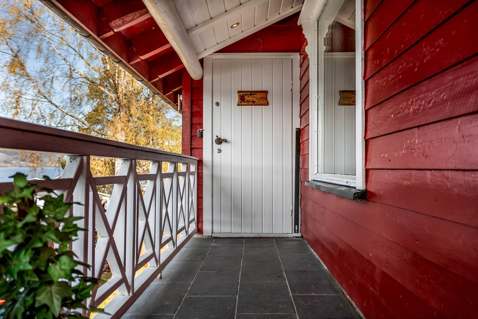 Overbygget inngangsparti med flislagt gulv. Ytterveggene har liggende trekledning, som gir et klassisk hyttepreg. Galleribilde