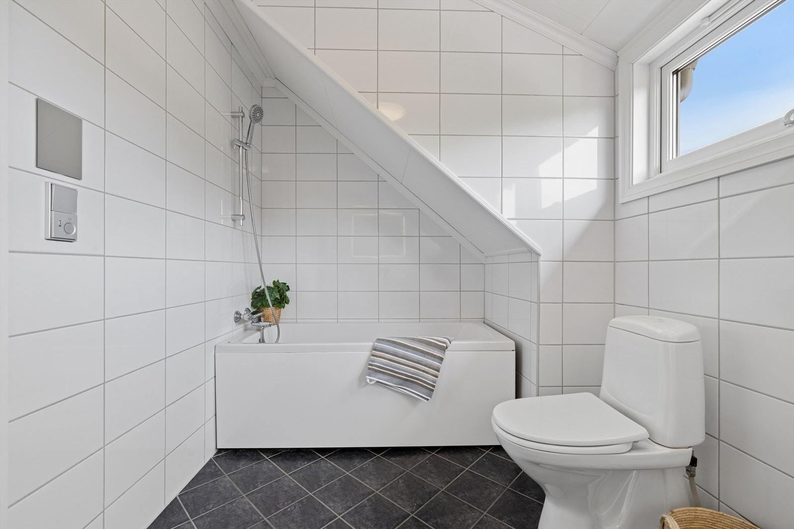 Rommet er innredet med toalett, badekar med dusj samt heldekkende servant nedfelt i underskap, med stort speil med integrert belysning over. Galleribilde