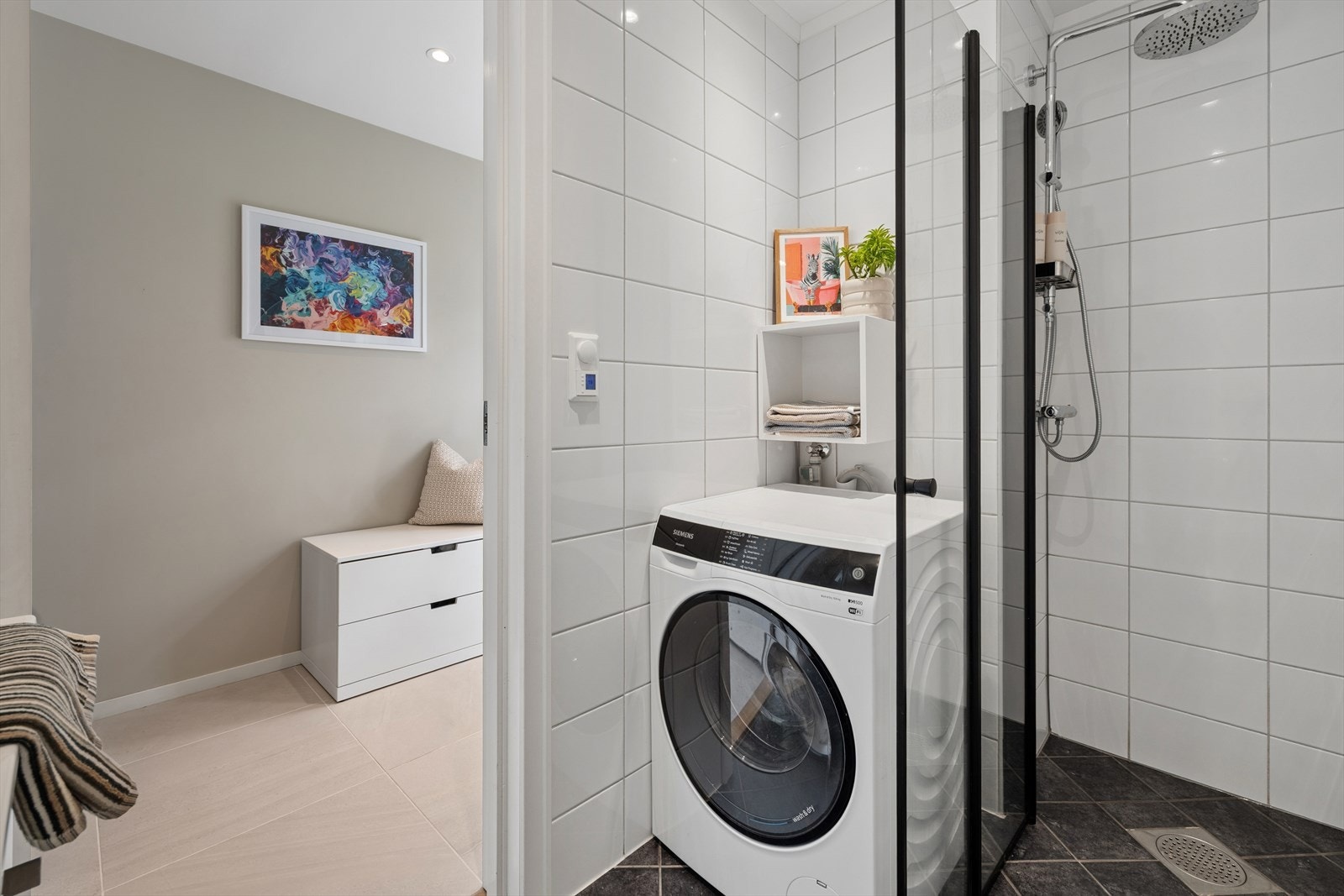 Rommet er innredet med vegghengt toalett, dusjnisje og servant integrert i moderne skuffeinnredning med speil og belysning. Opplegg for vaskemaskin, og rommet ventileres via balansert ventilasjonsanlegg. Galleribilde