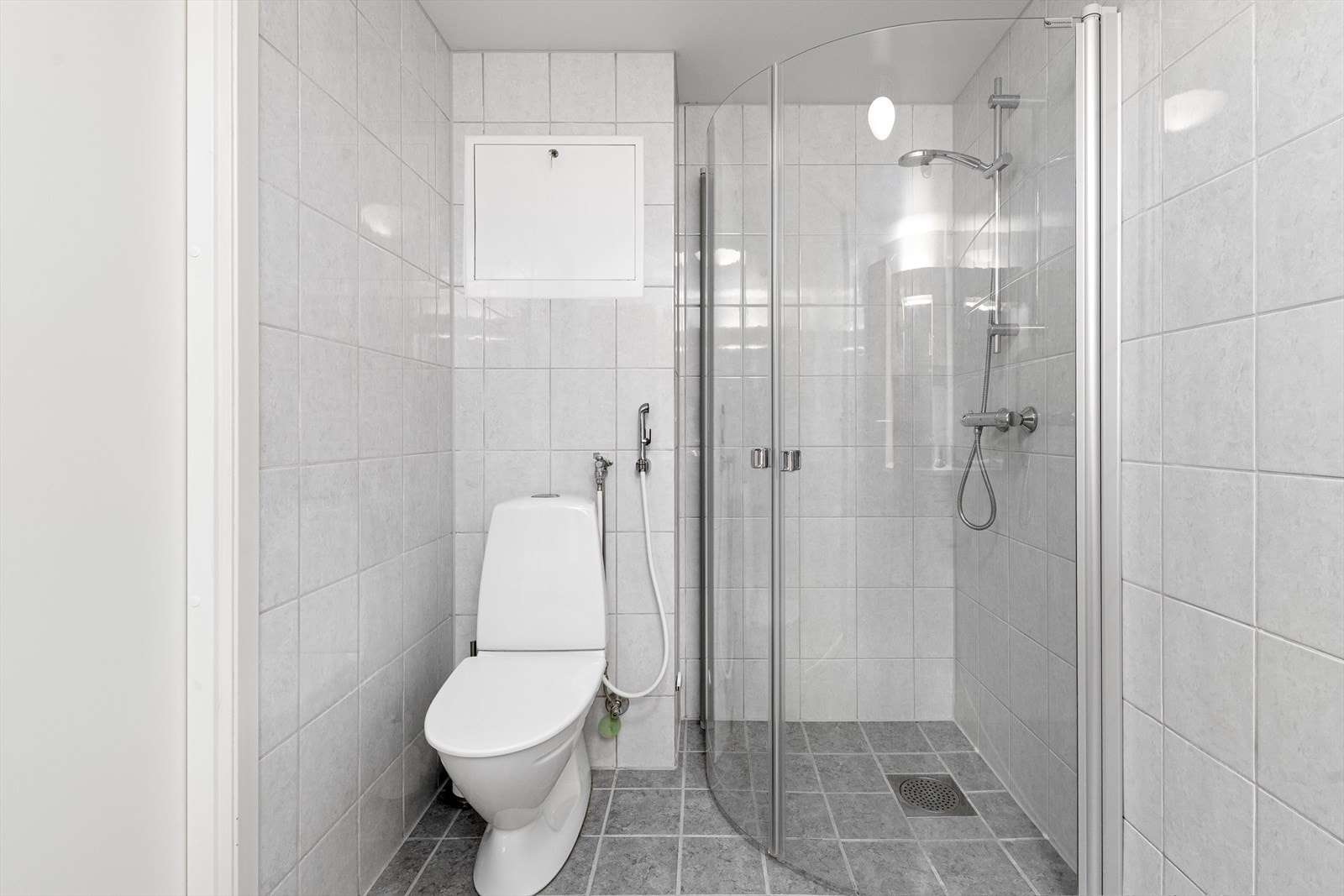 Badet er utstyrt med toalett og dusjhjørne med innfellbare glassdører. Galleribilde