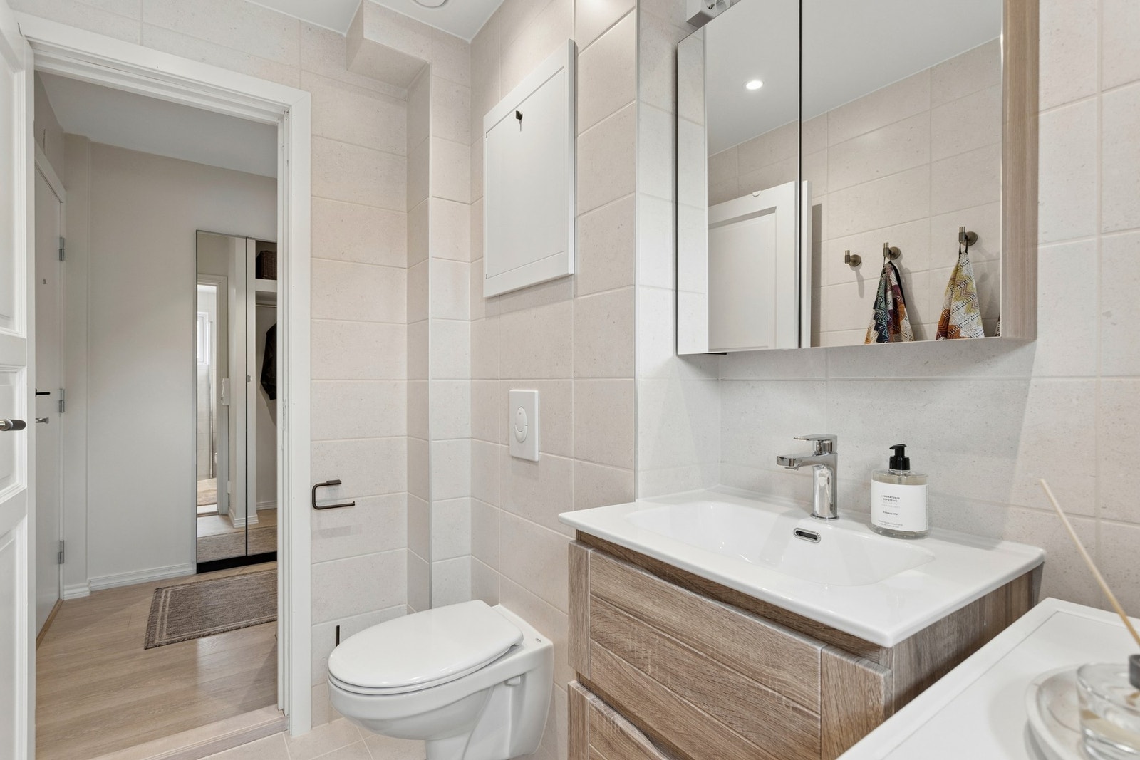 Badet er flislagt og har gulvvarme. Over vasken henger det et speilskap, praktisk for ekstra oppbevaring. Galleribilde