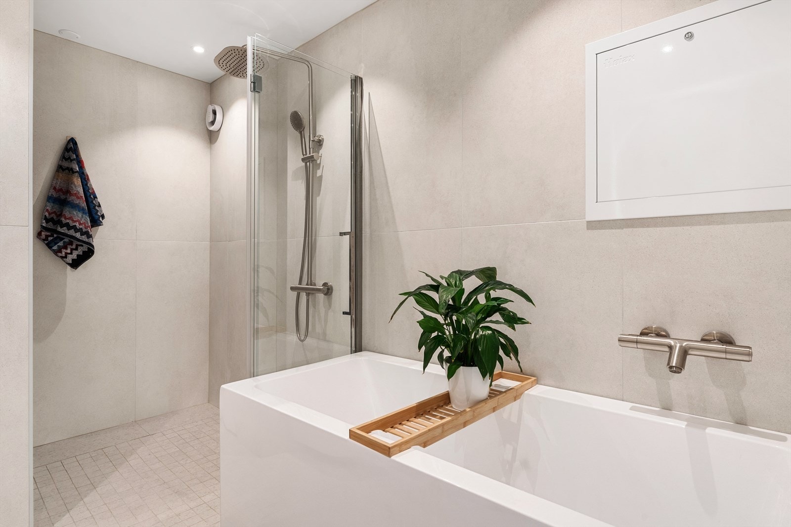 Badet er utstyrt med vegghengt toalett, foldedør i dusj, badekar, servant med baderomsinnredning, speil med belysning samt opplegg for vaskemaskin Galleribilde