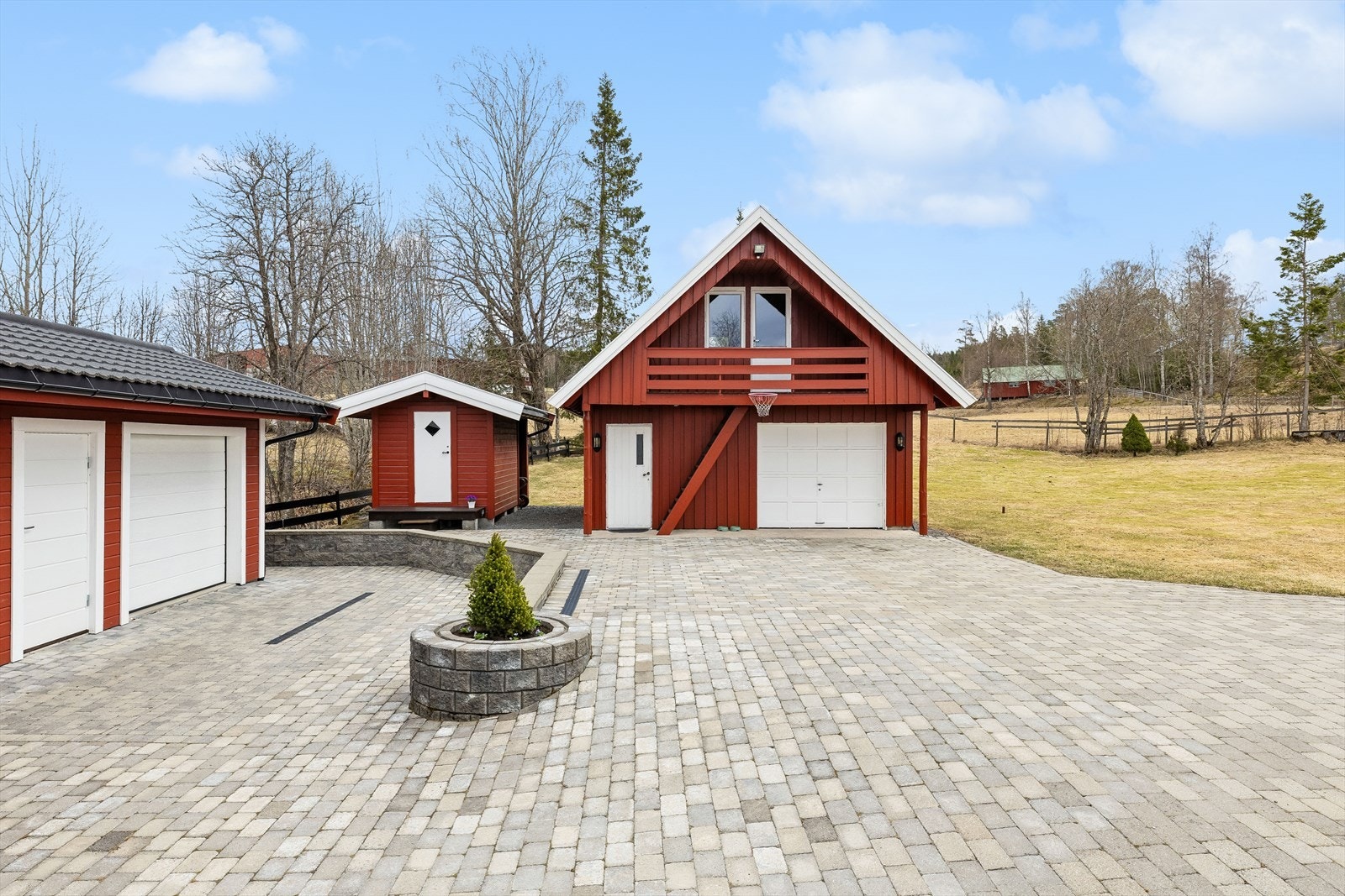 Gårdsplassen er pent opparbeidet med belegningsstein. Adkomst til 2 av eiendommens 4 garasjeplasser. Galleribilde