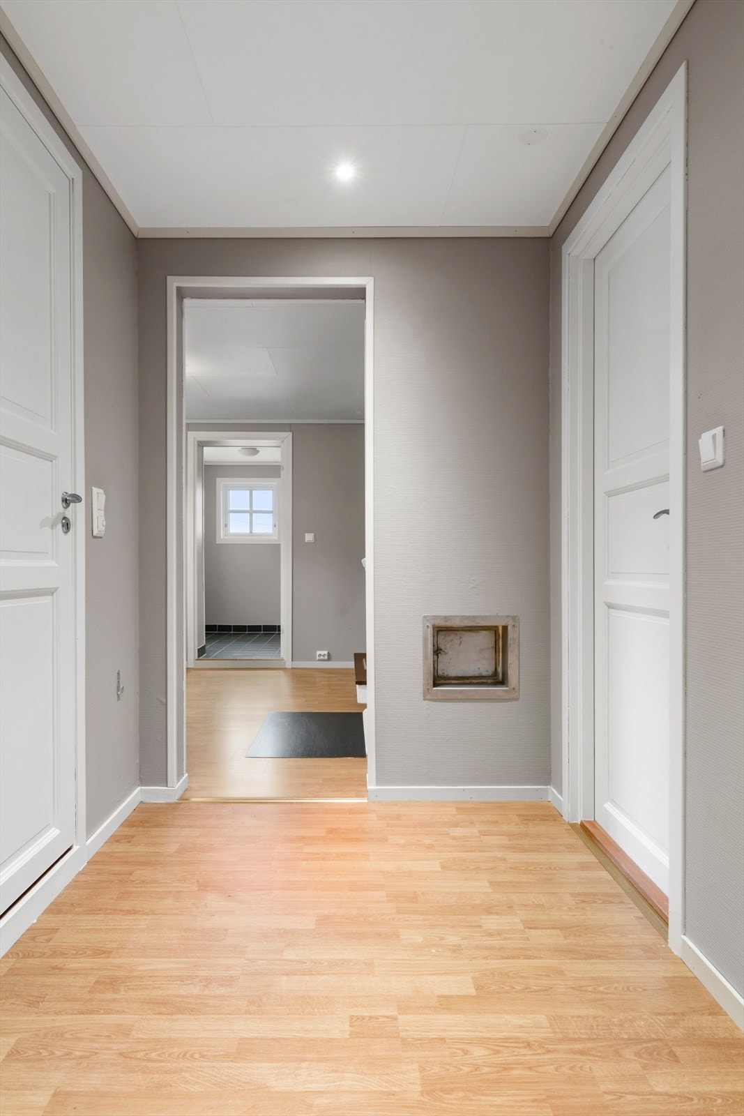 Dere kommer ned trappen og inn i denne gangen som fører til bad til venstre, soverom til høyre og videre inn i etasjen rett frem. Galleribilde