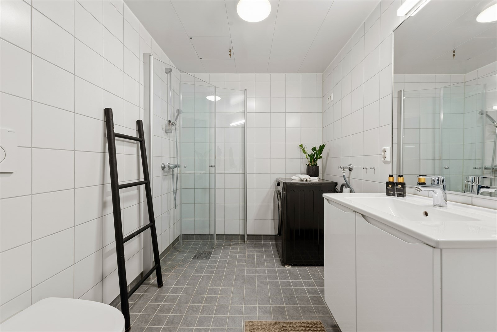 Badet er praktisk innredet med dusjhjørne, vegghengt toalett og opplegg for vaskemaskin. Galleribilde