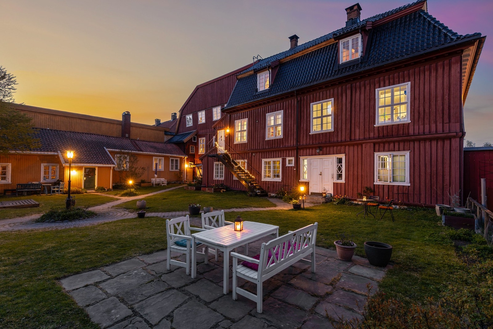 Bakgården er en skjermet oase med sittegrupper, gressplen, frodige blomsterbed og masse boltreplass Galleribilde