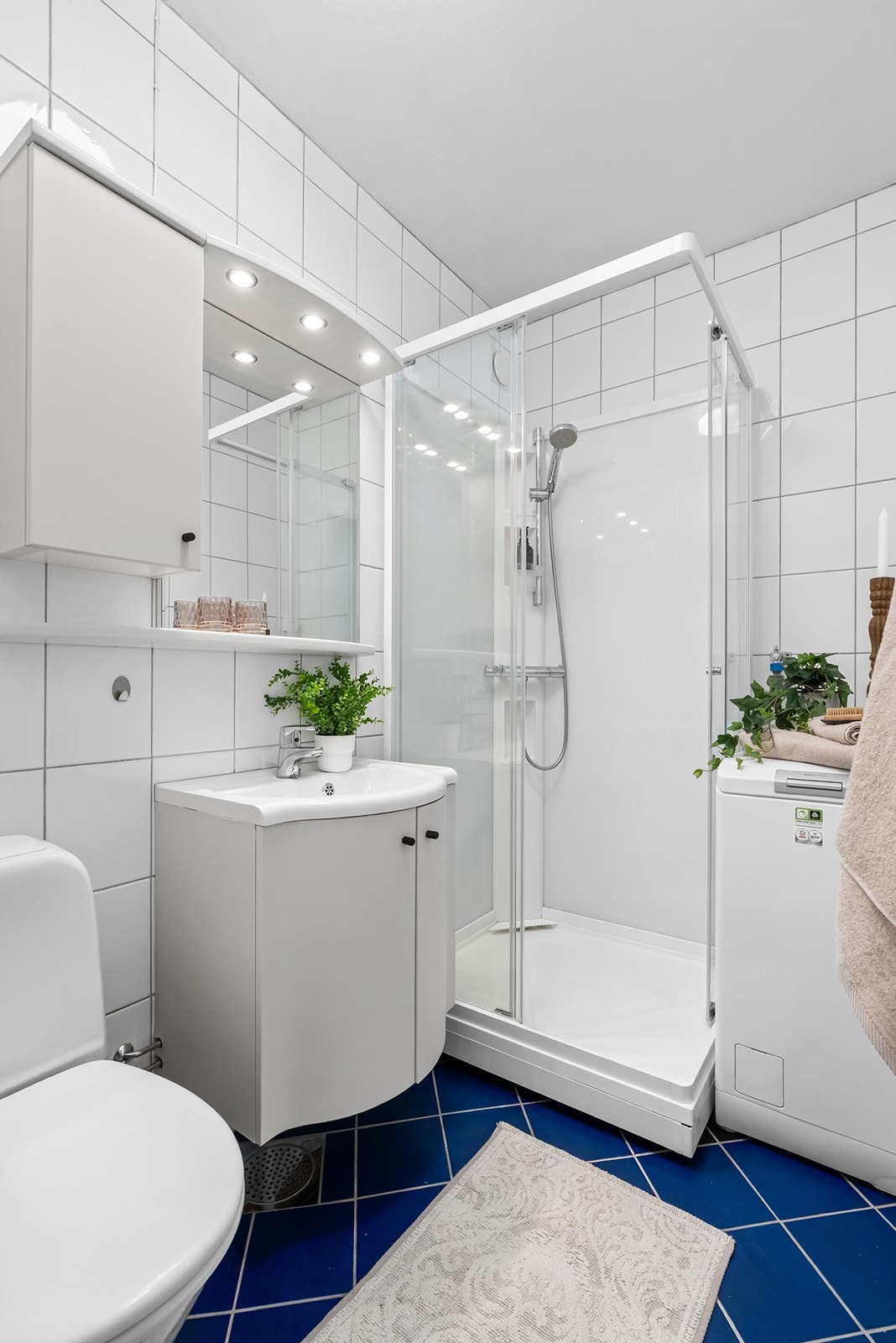 Badet har himling i malt betong, og er innredet med klosett, servant med innredning og dusjkabinett. Det er opplegg for vaskemaskin, og rommet har naturlig avtrekk. Galleribilde