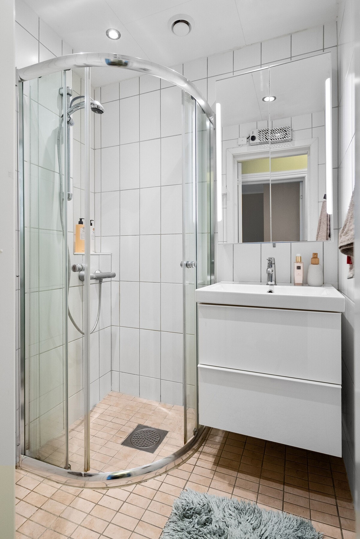 Lyst og tidløst flislagt bad med servant, servantskap, dusjhjørne, opplegg for vaskemaskin og downlights i himling. (TG 2 av takstmann) Galleribilde