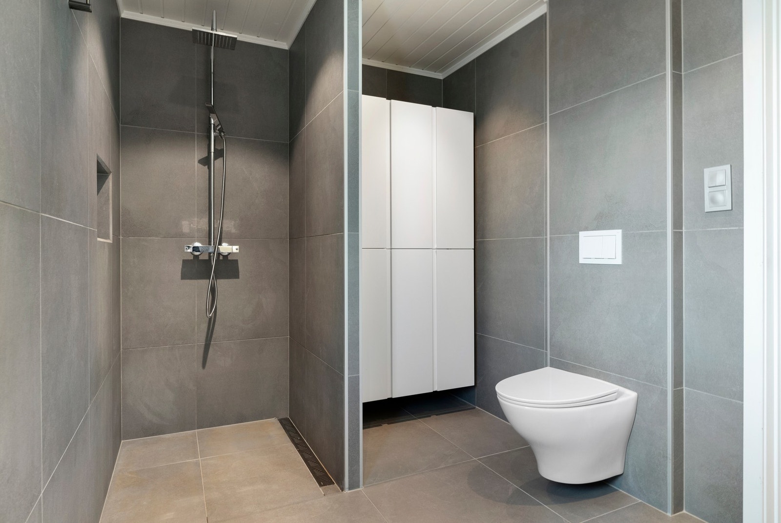 Badet er utstyrt både med dusjnisje, vegghengt toalett og servant med skap. Galleribilde