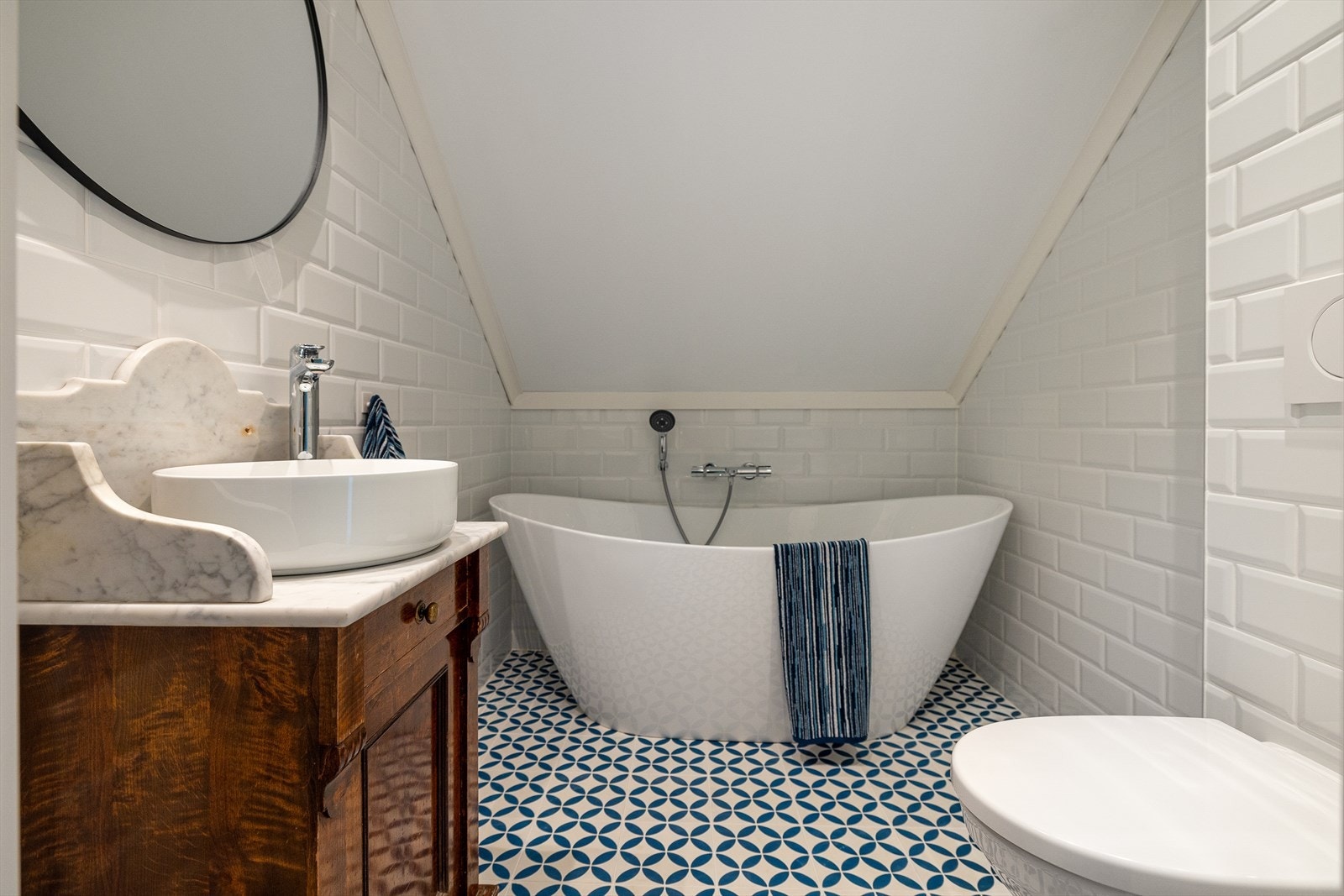 Badet i 2. etasje med frittstående, skålformet badekar og antikk innredning med servant plate i marmor. Galleribilde