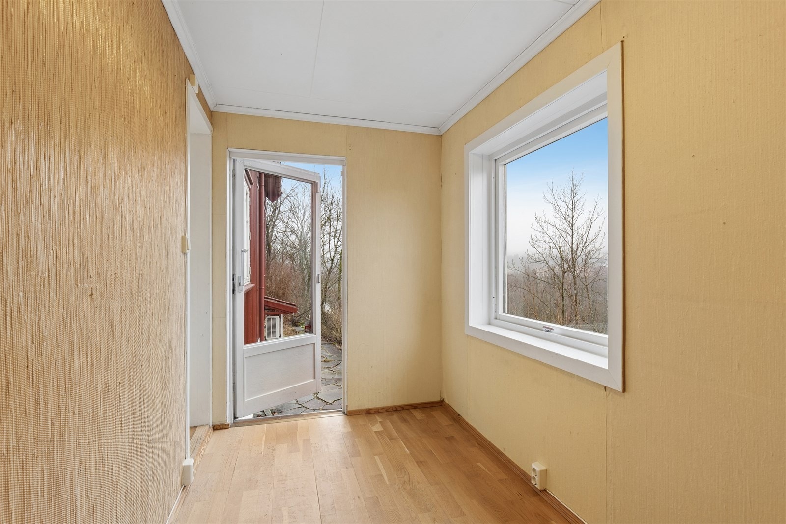 Tilstøtende rom fra stuen med stråtapet, malte vegger og utgang til hagen. Galleribilde