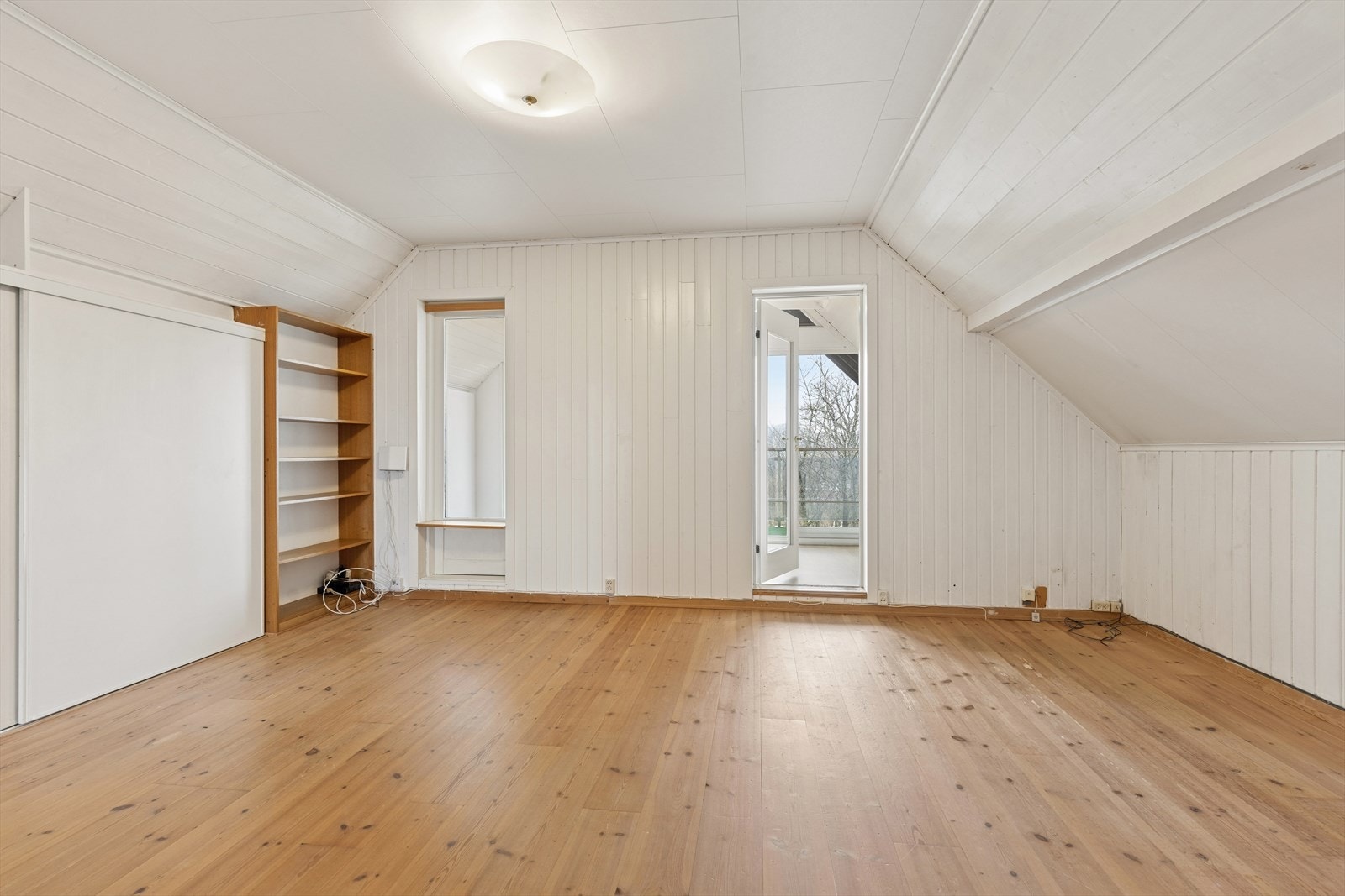 Soverom/loftstue med panelvegger, skråtak, tregulv og åpning ut mot "vinterhage" og veranda. Galleribilde