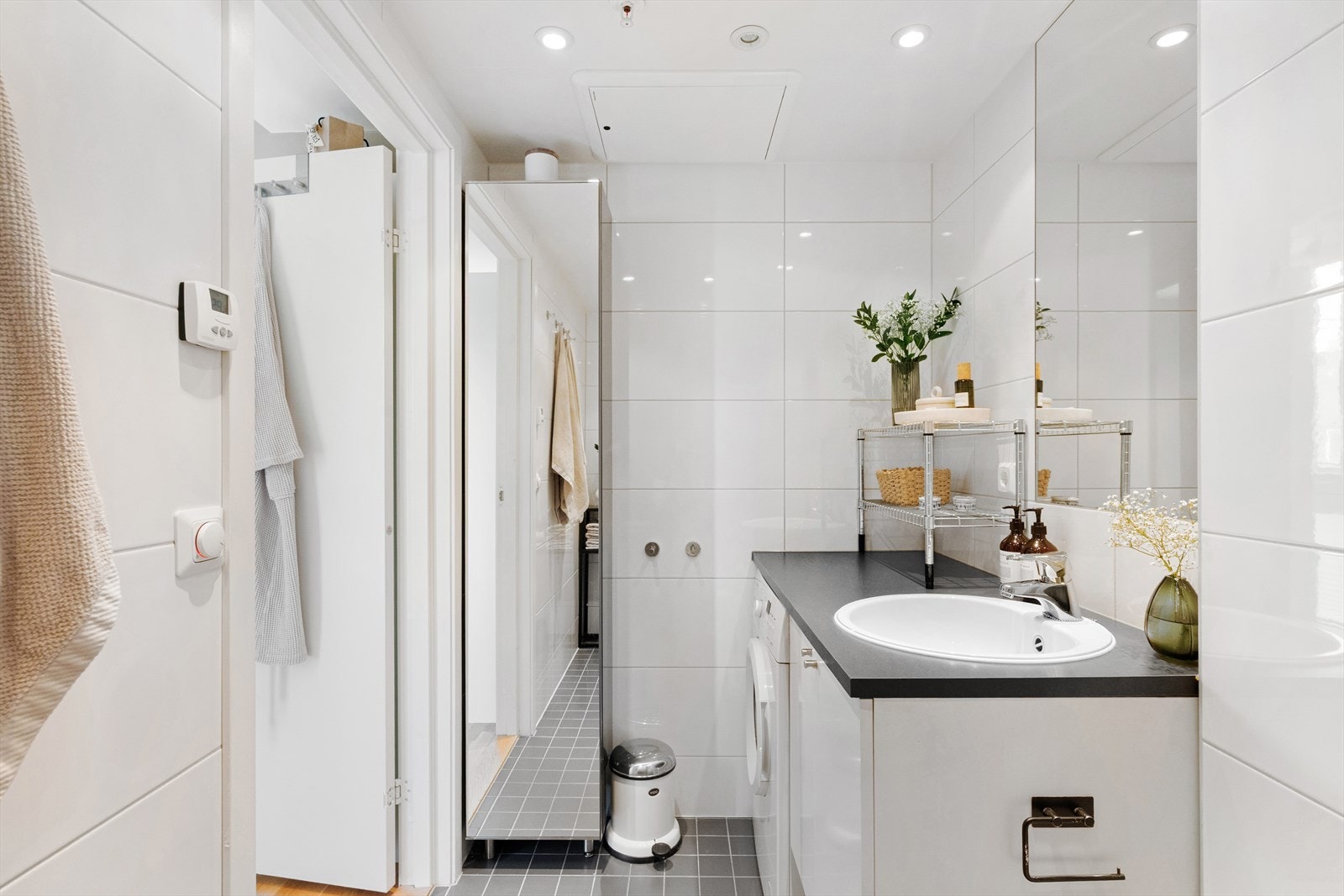 Badet er innredet med benkeplate med servantskap og nedfelt servant, innmurt speil og praktisk veggskap. Videre har badet vegghengt toalett og dusjhjørne med innfellbare dusjdører. Galleribilde