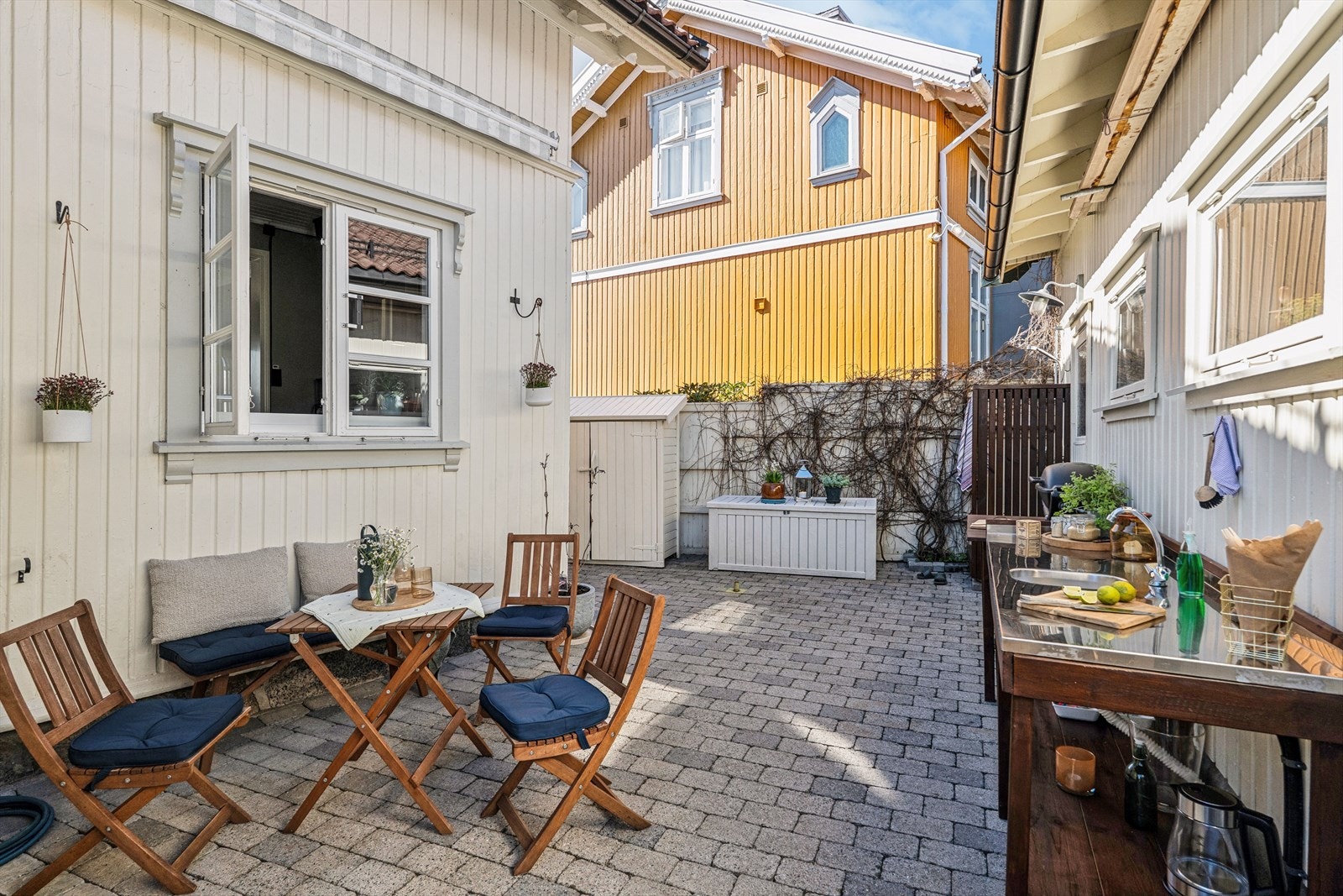 Den steinbelagte gårdsplassen mellom hovedhuset og uthuset skaper et lunt og privat uterom. Galleribilde