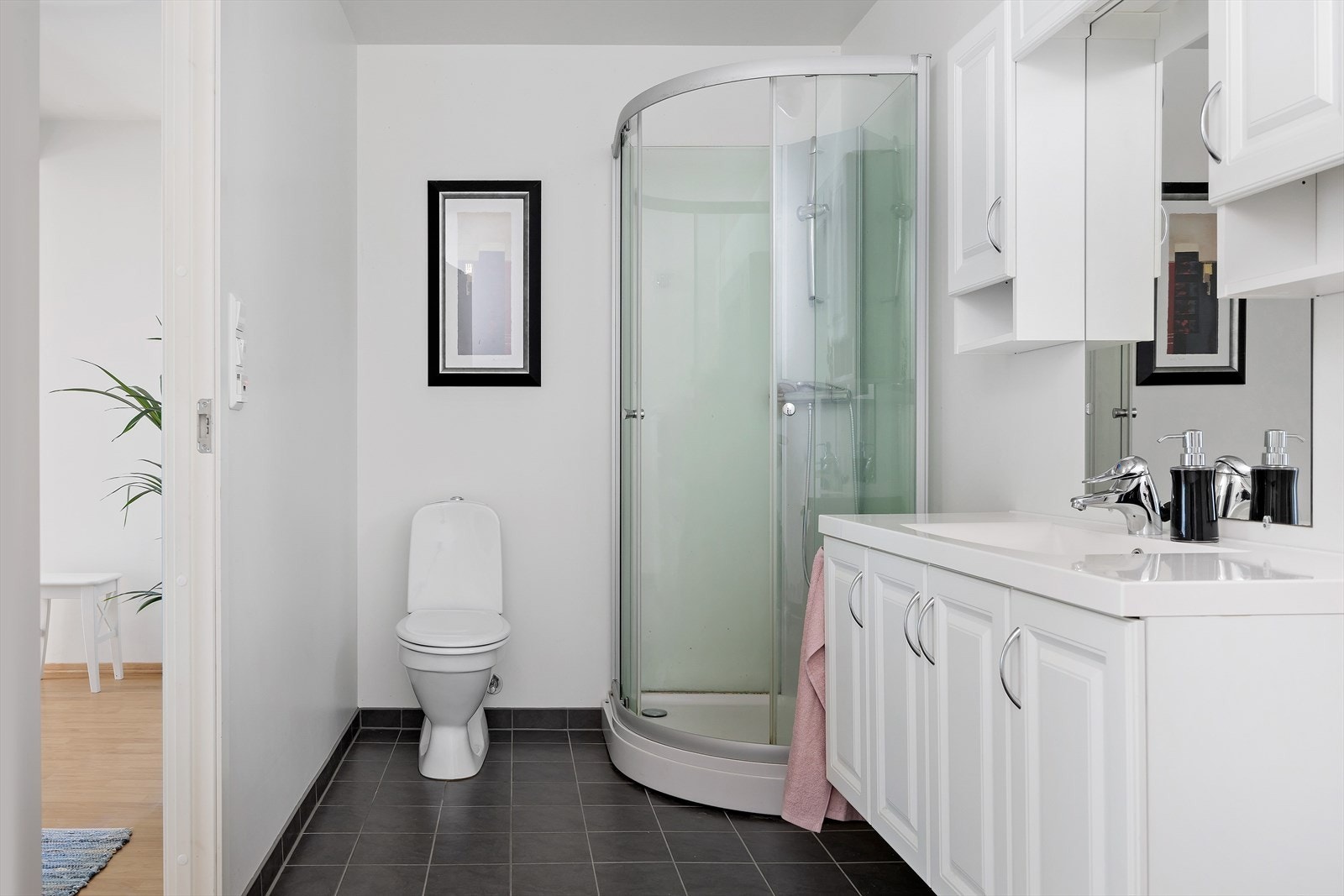 Badet i første etasje har flislagt gulv med varmekabler, dusjkabinett og servant med oppbevaring. Galleribilde