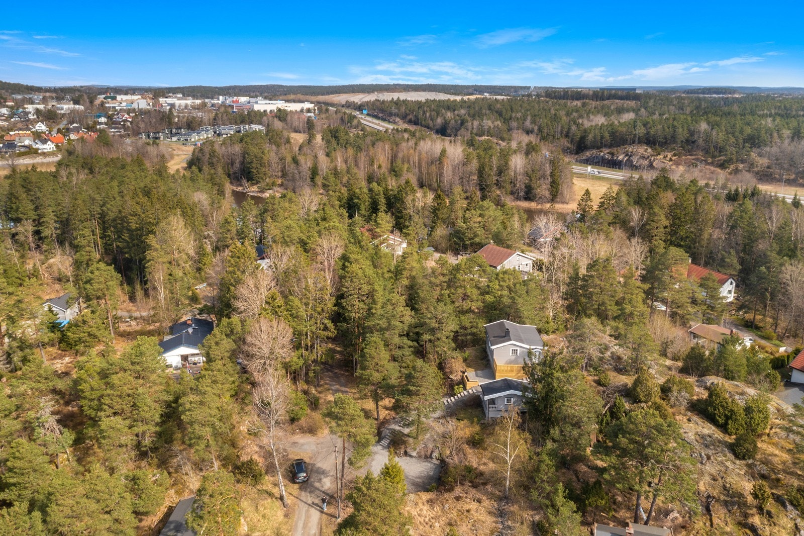 Tomten er en pen naturtomt som er plassert fint inn i det omkringliggende skogsterrenget. Den store grusplassen til høyre er parkeringsplass til hytta Galleribilde