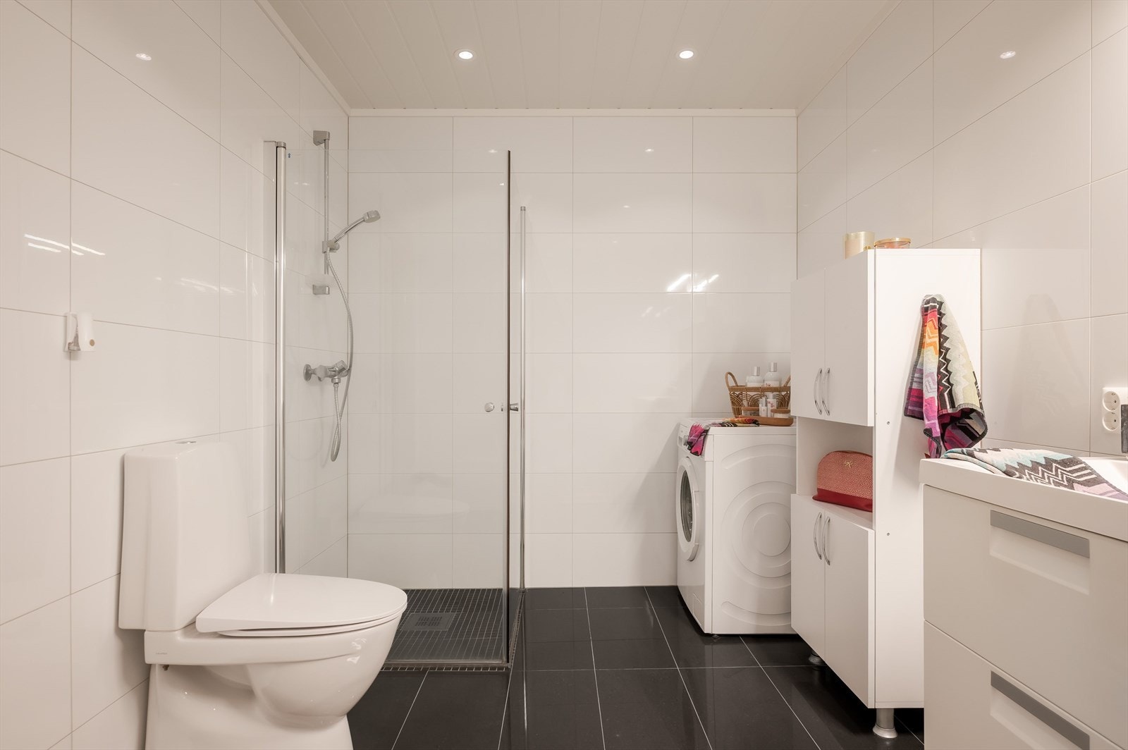 Badet er romslig og inneholder toalett, hjørnedusj, dobbelservant og opplegg for vaskemaskin. Galleribilde