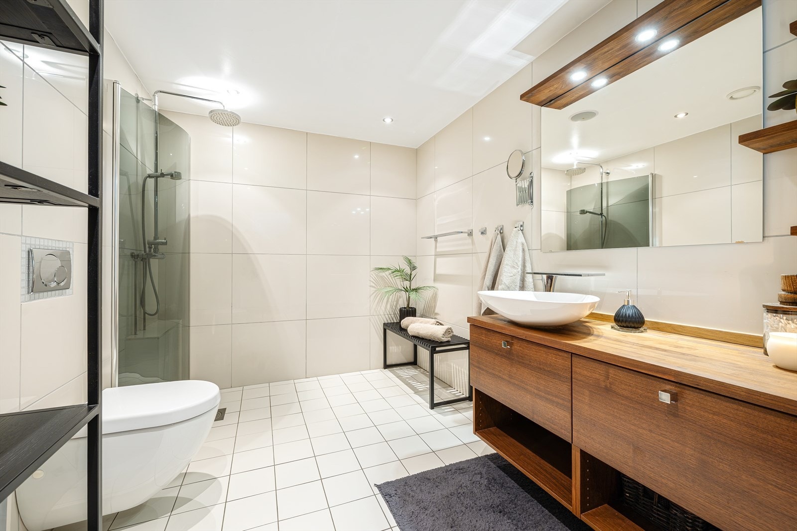Delikat og romslig bad i 1. etasje med gjennomførte, flislagte flater i lyse toner. Badet er utstyrt med moderne dusjløsning og stilren baderomsinnredning som sammen gir et elegant og tidløst uttrykk. Galleribilde