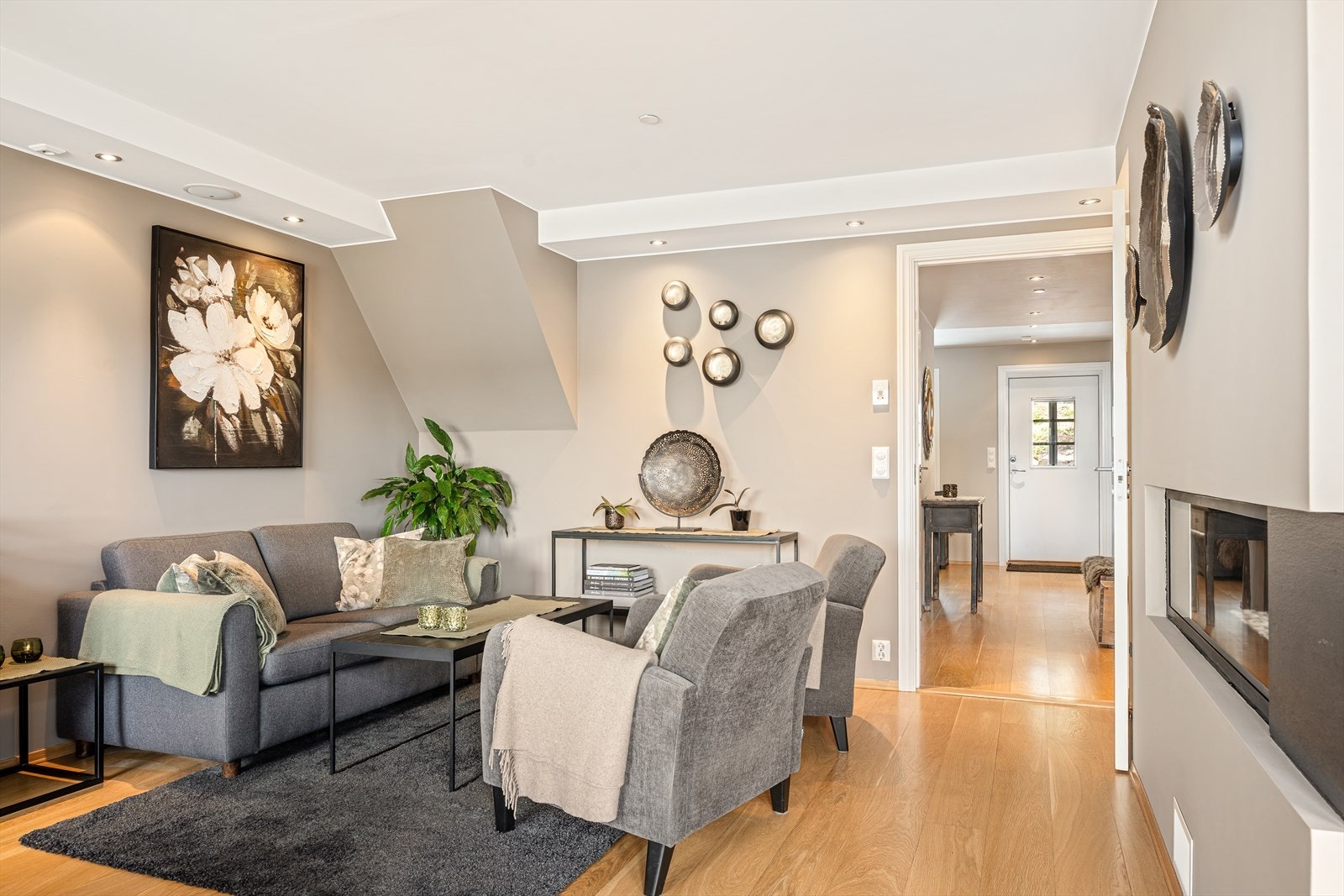 Veggene er malt i en lys og varm gråtone med diskrete beige undertoner, som gir rommet et elegant og tidløst uttrykk. Fargevalget bidrar til en lun og behagelig atmosfære. Galleribilde