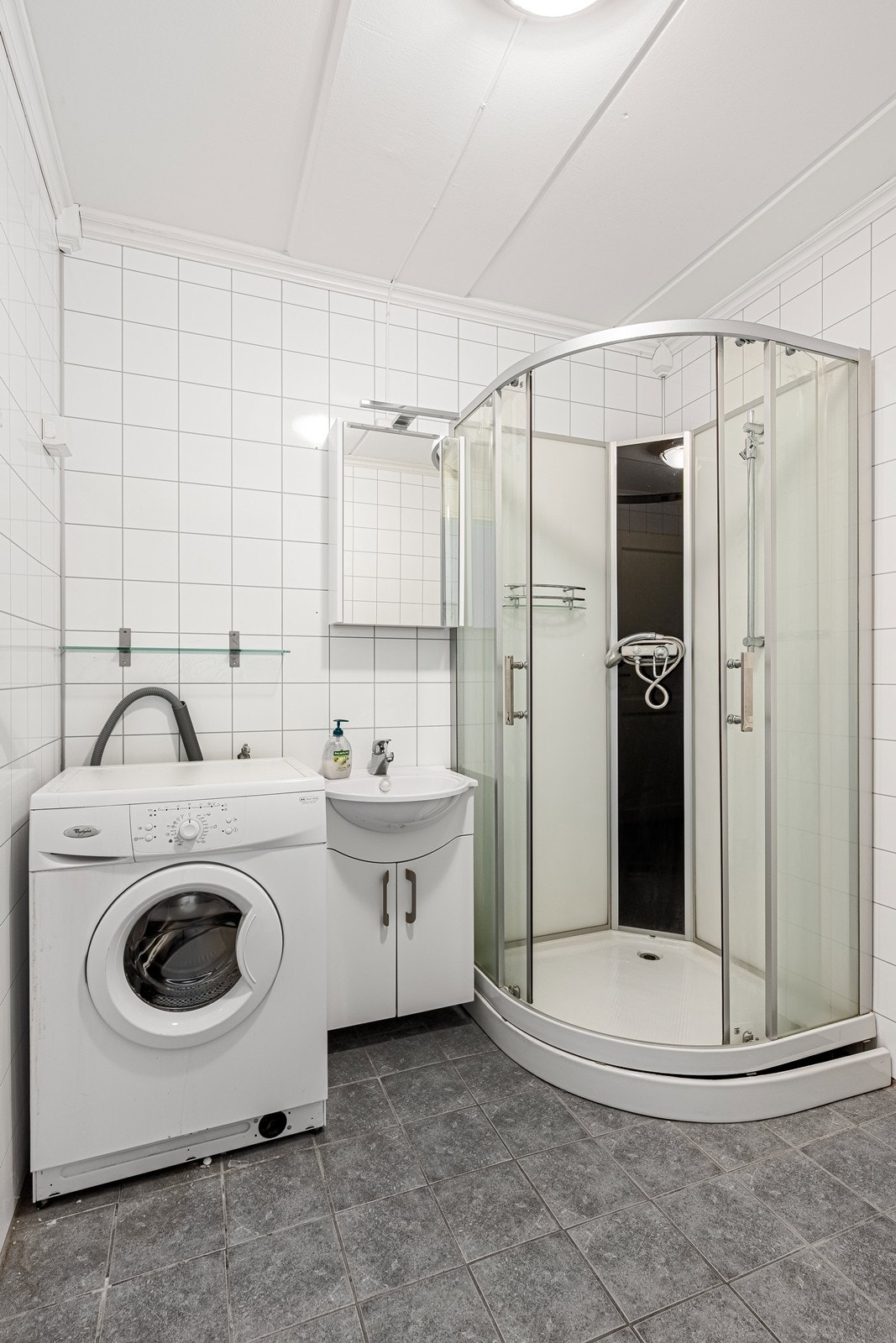 Badet inneholder dusjkabinett, WC, servantskap og veggskap med speilfronter. Galleribilde