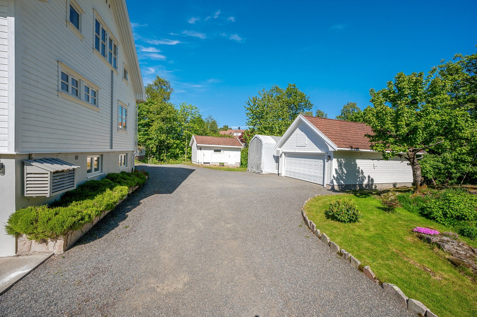 På eiendommen ligger det både en dobbel garasje med loft, frittliggende bod og stort tun for parkering av flere biler. Galleribilde