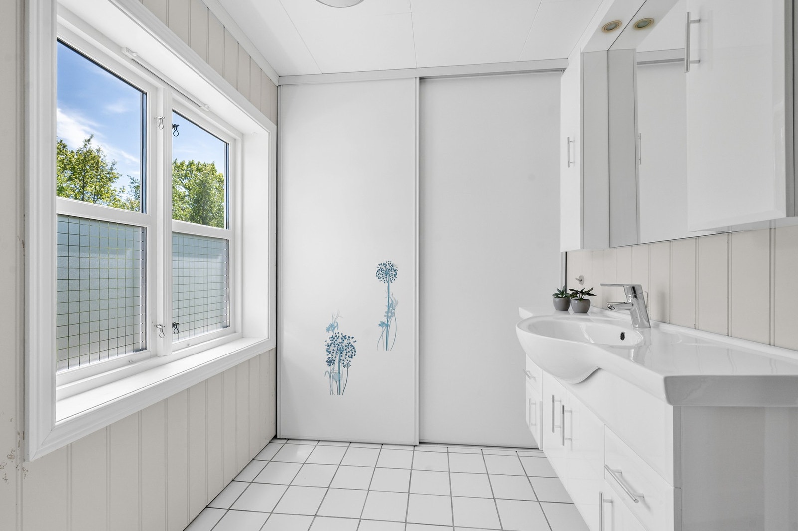 Bad i 1. etasjen med fliser på gulv med varmekabler. Her finner man både dusjnisje, innredning med servant og toalett. Galleribilde