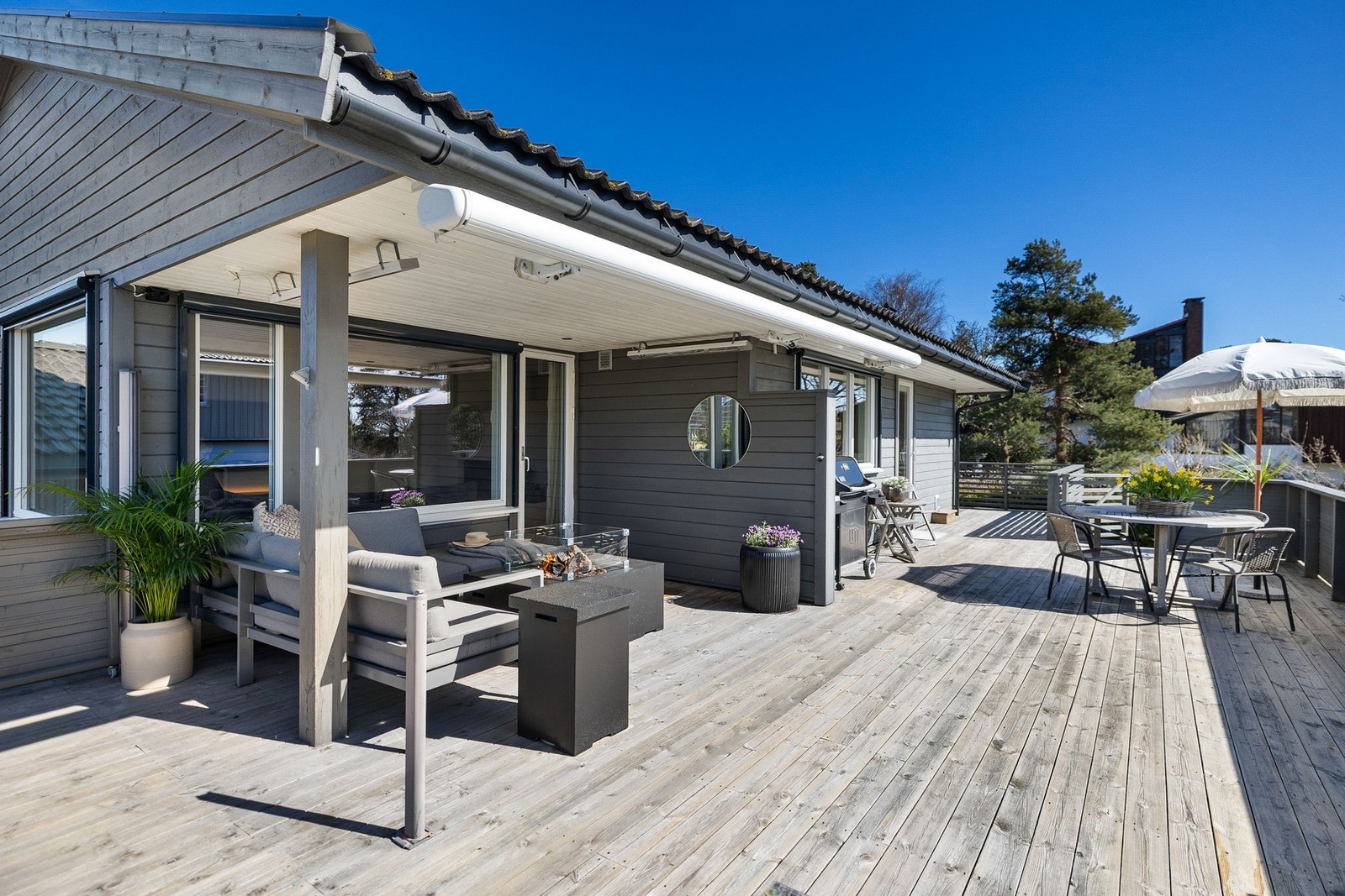 Stor, solrik terrasse med plass til både sittegruppe og spisebord, perfekt for utendørs aktiviteter. Galleribilde