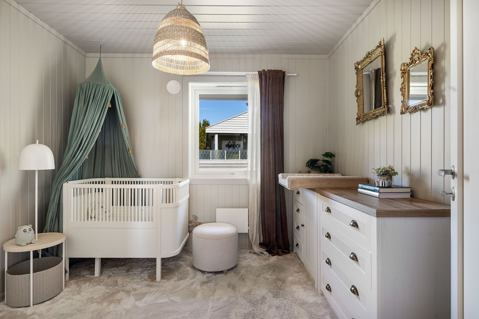 Lyst barnerom med vindu som slipper inn naturlig lys og panelerte vegger. Galleribilde