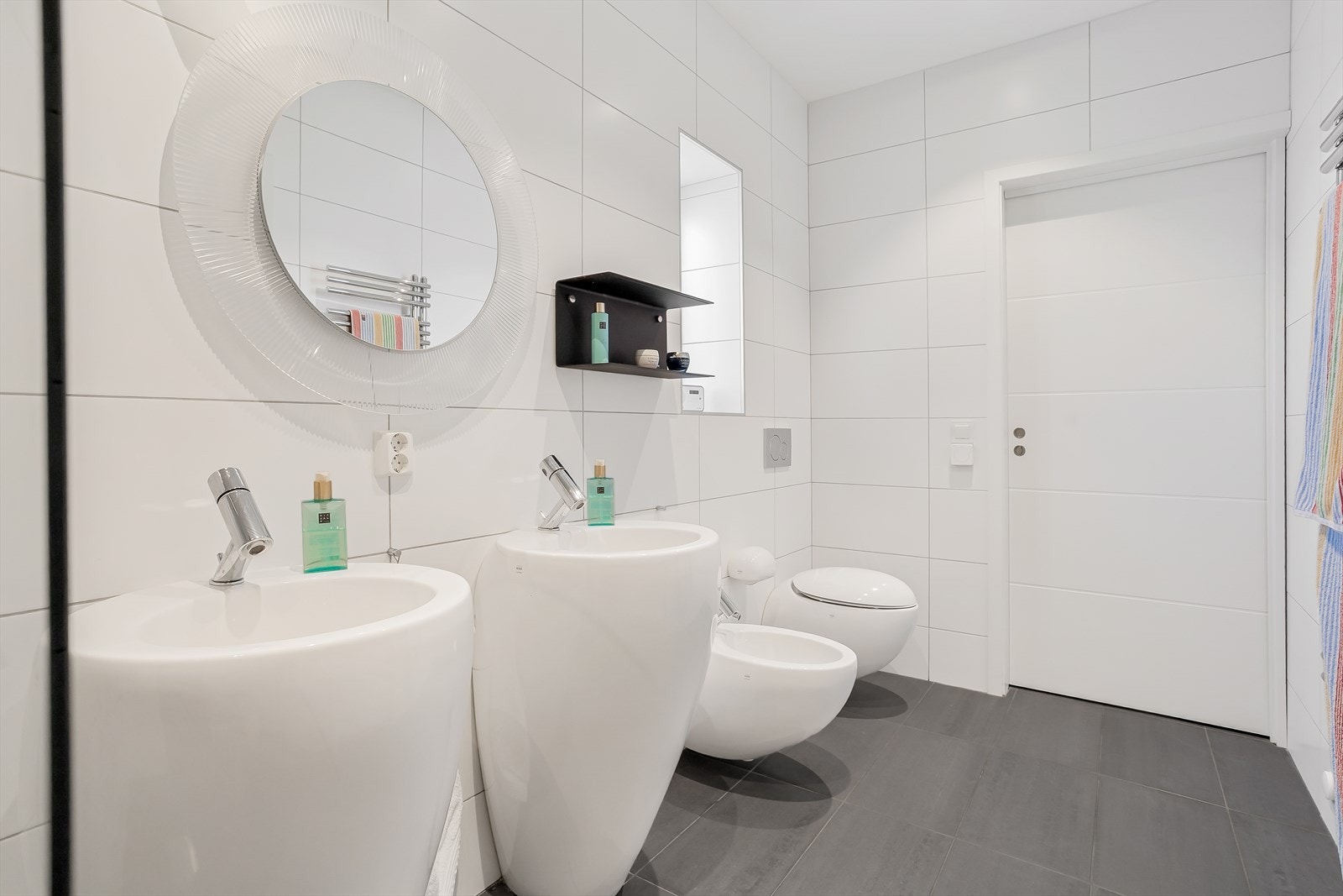 Hovedbadet er utstyrt med to servanter, fotvask og vegghengt toalett. Galleribilde