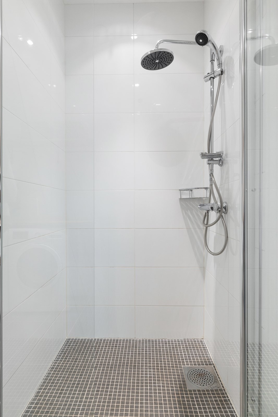 Badet er utstyrt med dusjnisje med innfellbare glassdører, veggmontert wc, mekanisk avtrekk og opplegg for vaskemaskin. Rørfordelingsskap er også plassert i rommet. Galleribilde