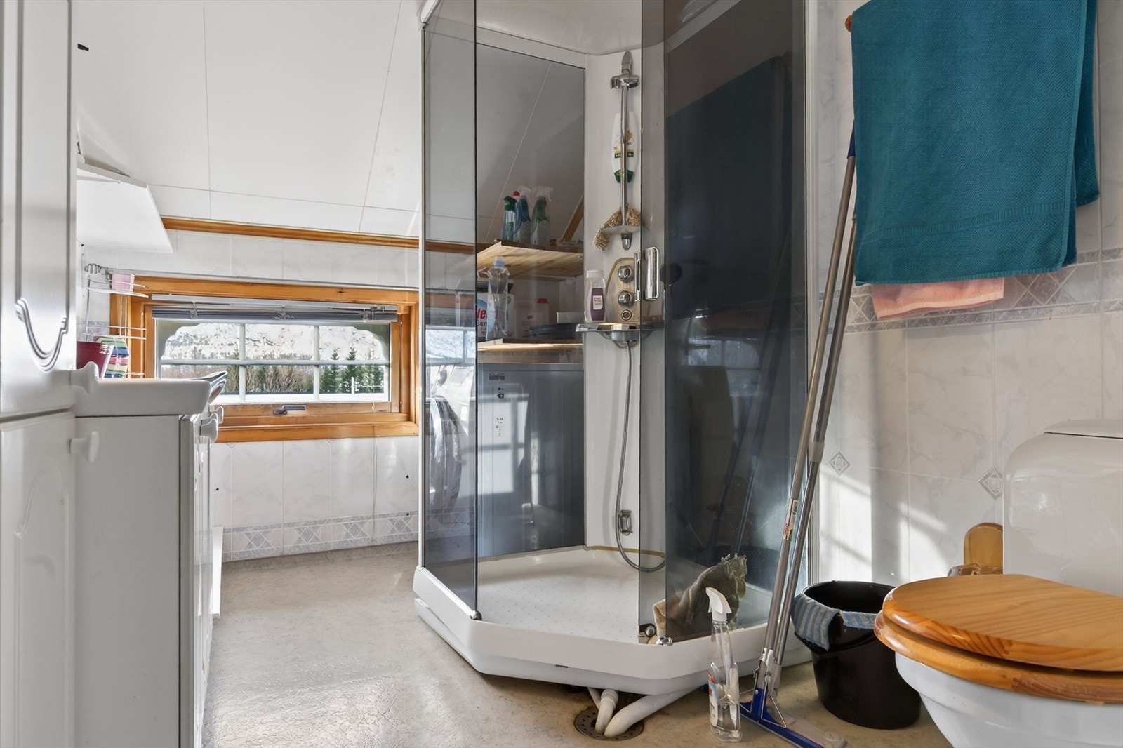 Lyst bad med moderne dusjkabinett og praktisk oppbevaringsplass. Vindu som gir naturlig lys. Galleribilde