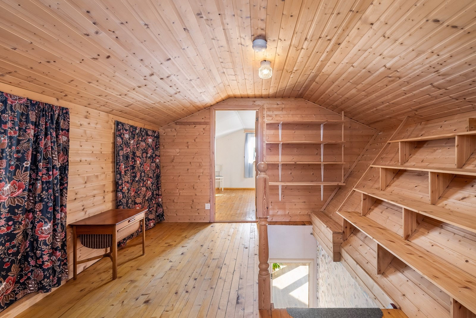 Med trapp fra første etasje kommer en opp i en gang/liten loftstue. Her er det godt med hyller og lagringsplass Galleribilde