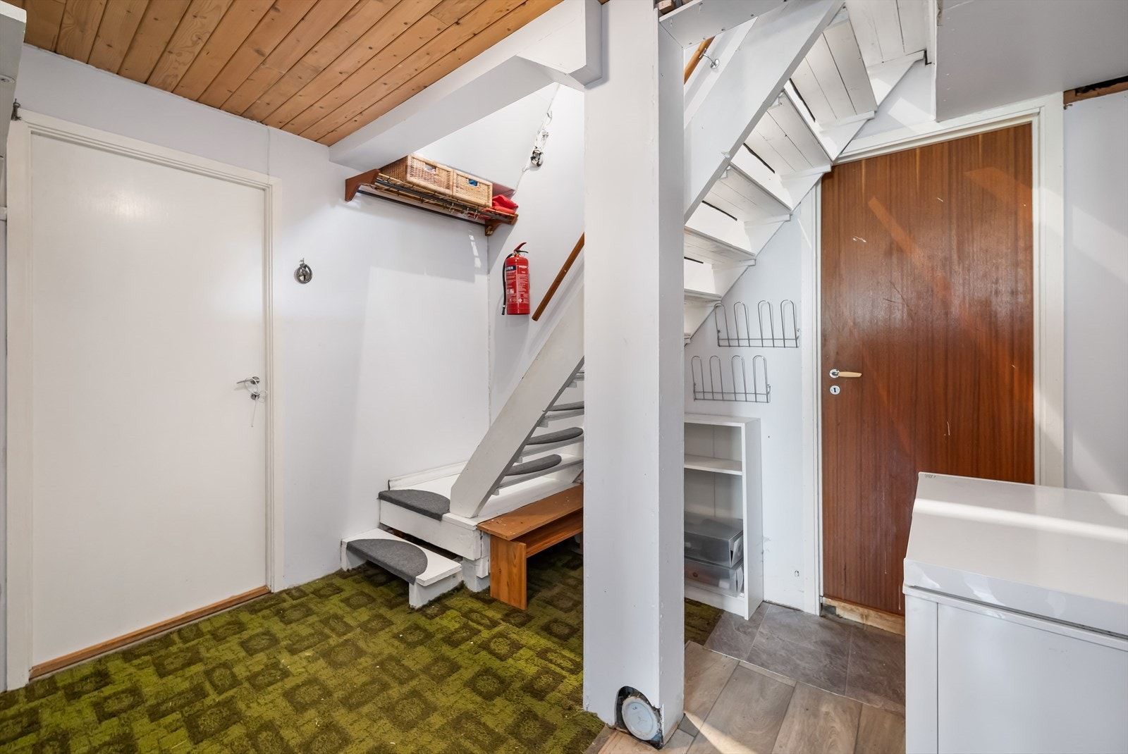 Fra første etasje kommer en ned i en stor gang/trapperom. Rommet ligger midt i huset med dører flere av bodene. Overflatene er grove og rustikke. Galleribilde
