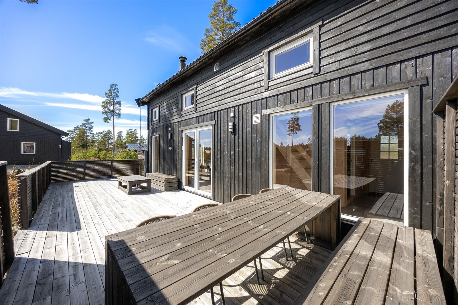 Terrassen har dekke og rekkverk i tre, og det er montert både utestikk og moderne utebelysning på hyttevegg Galleribilde