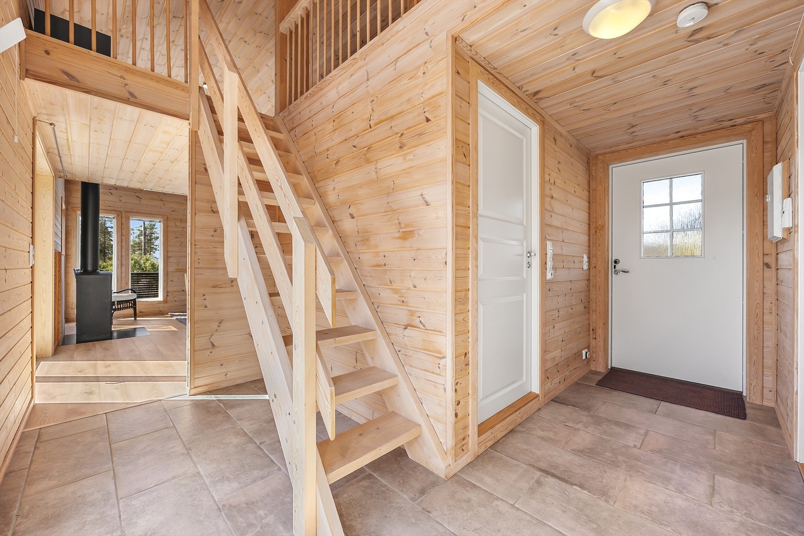 Vel inne blir vi ønsket velkommen i en fin entré med naturlig panel på veggene og lysegrå fliser på gulv med gulvvarme. Galleribilde