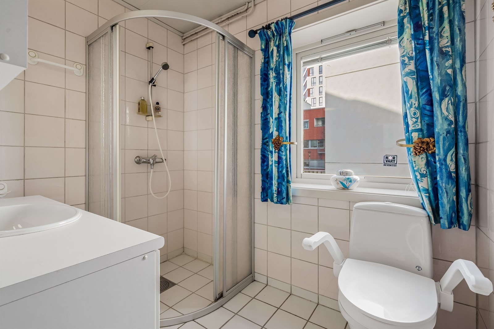 Badet har flislagte overflater i nøytrale farger og oppvarming med gulvvarme Galleribilde